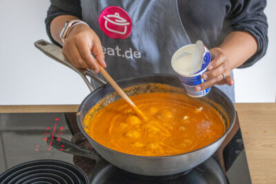 Sahne zum Shahi Paneer Curry gießen
