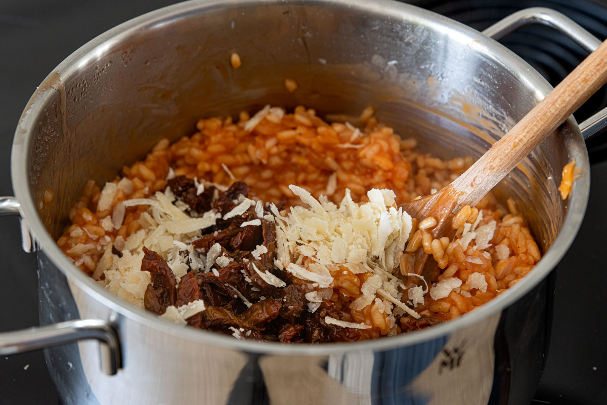 getrocknete Tomaten und Parmesan in das Risotto geben