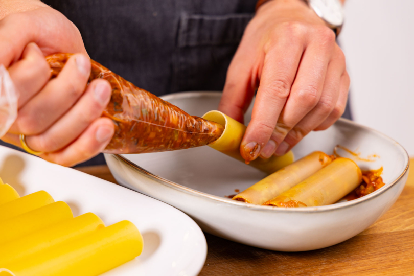 Hackmasse mit Spritzbeutel in Cannelloni füllen.