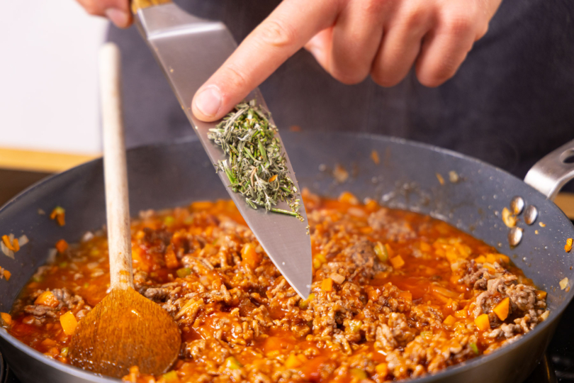 Kräuter zu der Soße geben.