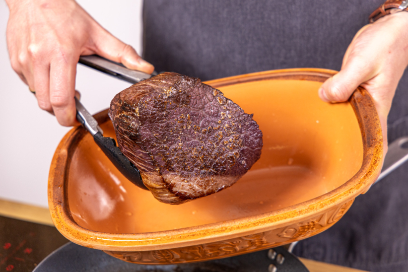 Angebratenes Fleisch in den Römertopf legen