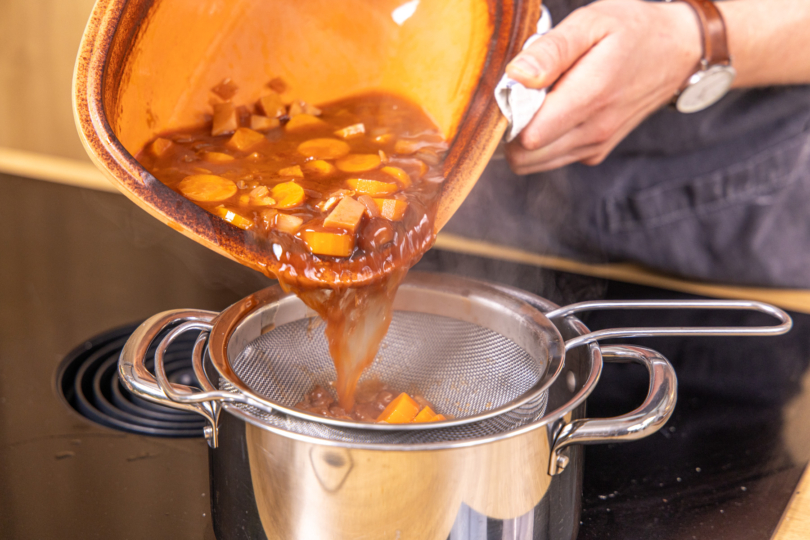 Soße durch ein Sieb gießen