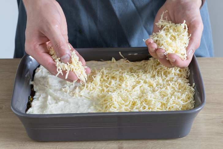 Gouda auf der vegetarischen Gemüselasagne verteilen