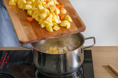Für Omas Kartoffelsuppe das Gemüse in den Topf geben