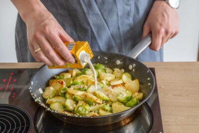 Vegane Sahne zur Rosenkohl-Kartoffel-Pfanne geben