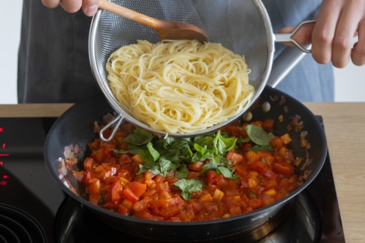 Spaghetti unter die Tomatensauce heben