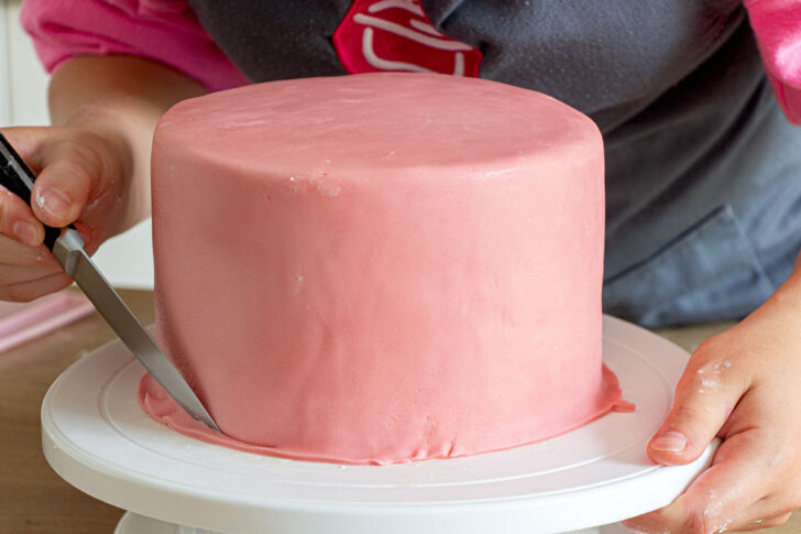 Fondant nach dem Überziehen an der Torte abschneiden