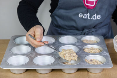 Teig für gesunde Frühstücksmuffins mit Haferflocken in Muffinform befüllen