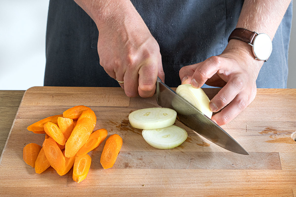 Karotten und Zwiebeln in Scheiben schneiden