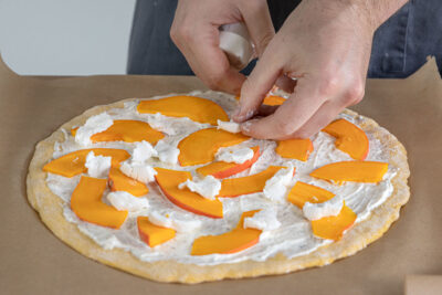 Ziegenkäse auf die Kürbis Pizza zupfen
