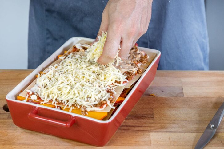 Gratinkäse über die Kürbislasagne mit Hackfleisch geben