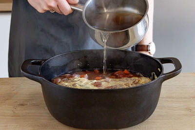 Brühe zum Schweinebraten gießen