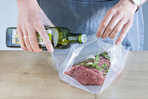 Fleisch mit Öl und Gewürzen in den Vakuumierbeutel geben