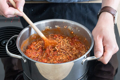 Hackfleisch und gehackte Tomaten köcheln lassen