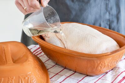 Ente in den Römertopf geben und mit Weißwein übergießen