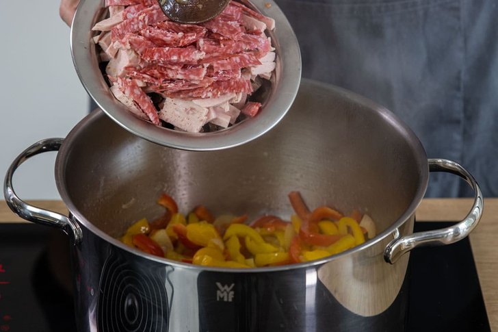 Salami und Jagdwurst in den Topf geben