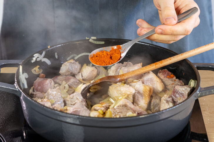 Paprikapulver zum Fleisch geben