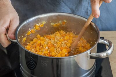 Nach dem Anrösten die Zutaten für die vegane Kürbis-Bolognese mit Sojaschnetzel gut im Topf vermischen