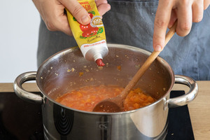 Tomatenmark in die vegane Kürbis-Bolognese mit Sojaschnetzel geben