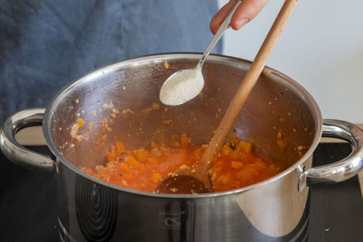 Zucker in die vegane Kürbis-Bolognese mit Sojaschnetzel geben