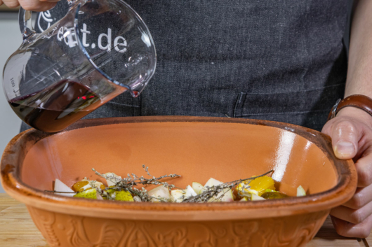 Rotwein in Römertopf gießen