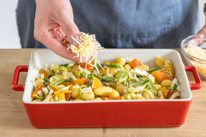 Vegetarischen Kürbis-Gnocchi-Auflauf mit Käse bestreuen