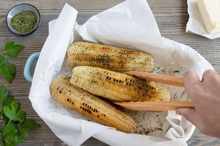 Maiskolben aus der Pfanne mit Butter und Kräutersalz