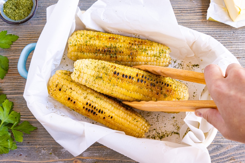 Maiskolben aus der Pfanne mit Butter und Kräutersalz