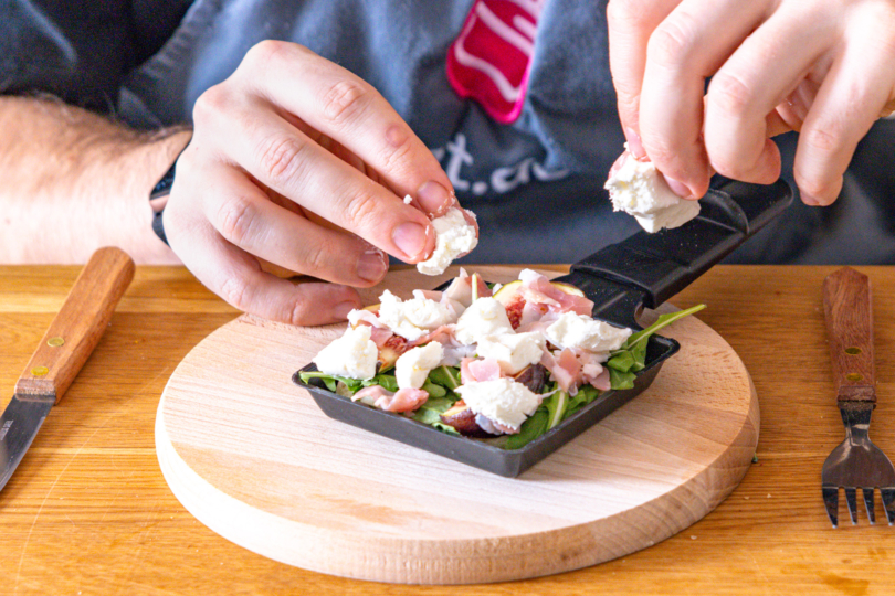 Ziegenkäse über belegte Raclette-Pizza bröseln