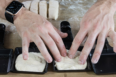 Pizzateig in Pfännchen verteilen