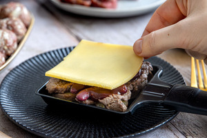 Raclettekäse auf dem Pfännchen verteilen