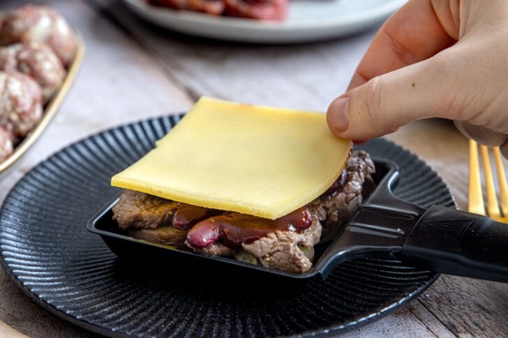 Raclettekäse auf dem Pfännchen verteilen