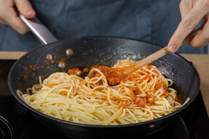 Spaghetti unter Soße rühren