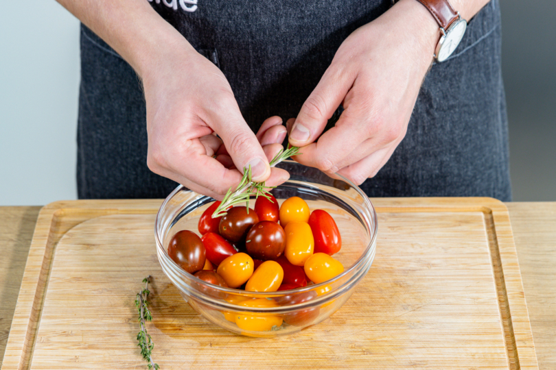 Kräuter zu den Tomaten geben