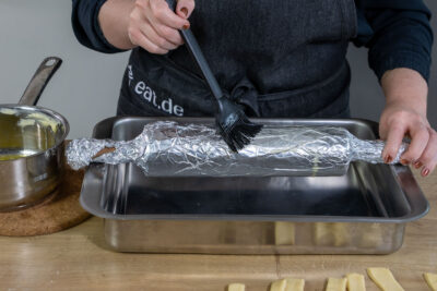 Nudelholz mit Alufolie einkleiden und mit Butter bepinseln