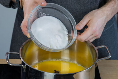 Zucker zum Orangensaft geben