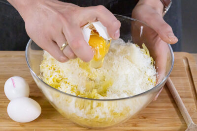 Pecorino und Ei zur Kartoffelmasse geben