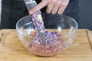 Die Zwiebeln und den Knoblauch zu dem Hackfleisch geben.