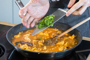 Koriander zum Thailändisches Massaman-Curry geben