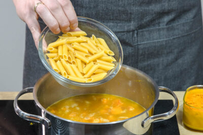 Für die One Post Kürbis-Pasta die Nudeln in die Brühe geben.