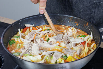 Gemüse und Hähnchenfleisch zum Curry geben