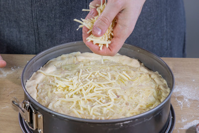 Käse über den Zwiebelkuchen geben