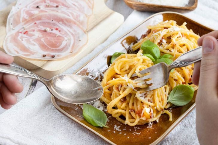 Spaghetti Carbonara Originale mit frischem Basilikum servieren.