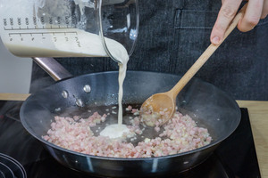 Sahne zum Speck in die Pfanne gießen