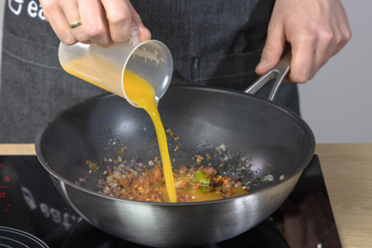 Mangosaft in den Wok gießen.