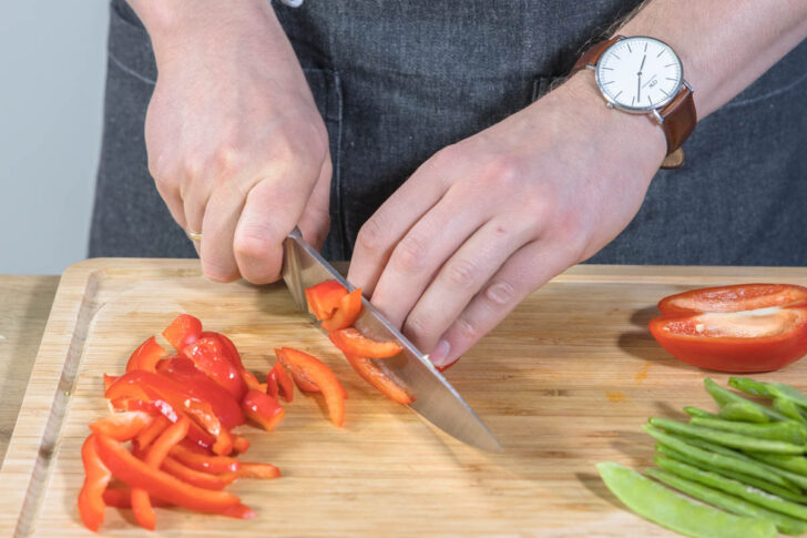 Zuckerschoten und Paprika in feine Streifen schneiden.