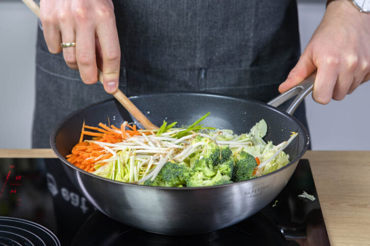 Das geschnittene Gemüse für das gelbe Thai Curry in den Wok geben.
