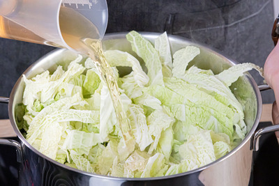 Geflügelbrühe zum Wirsinggemüse mit Speck gießen