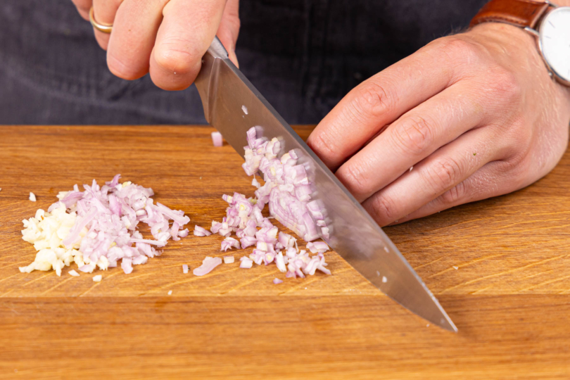 Schalooten und Knoblauch schälen und in feine Würfel schneiden