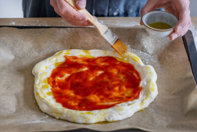 Pizza mit Tomatensoße bestreichen und vorbacken